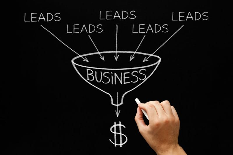 The Ultimate Guide to Getting Clients as a Solo Attorney 1 person holding a piece of chalk and drawing a lead generation funnel on a black wall