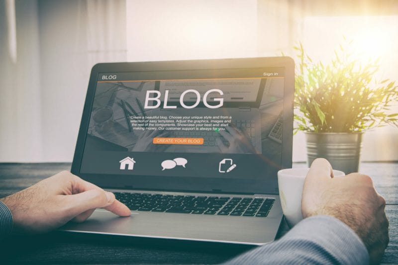 Blogging for Lawyers: How to Start & Grow Your Legal Blog 1 man holding a cup and working on his blog using his laptop